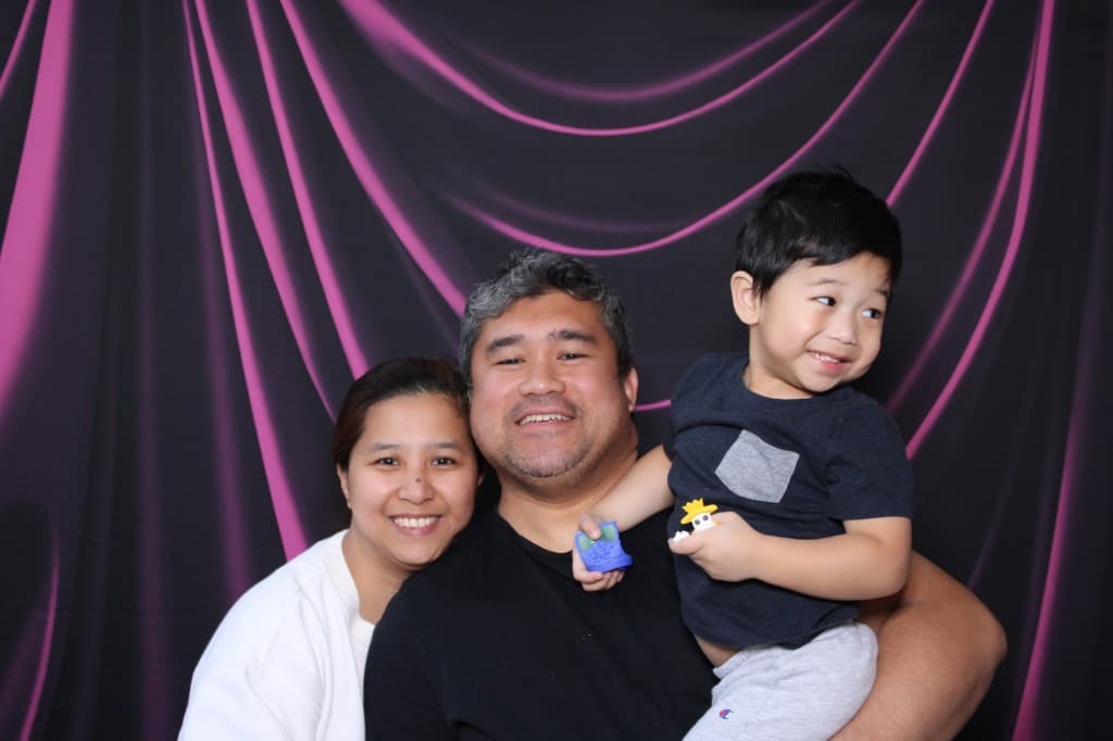 Family posing together at a magenta-lit booth backdrop